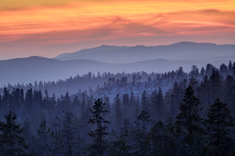 the mountains are covered in snow and trees at dusk