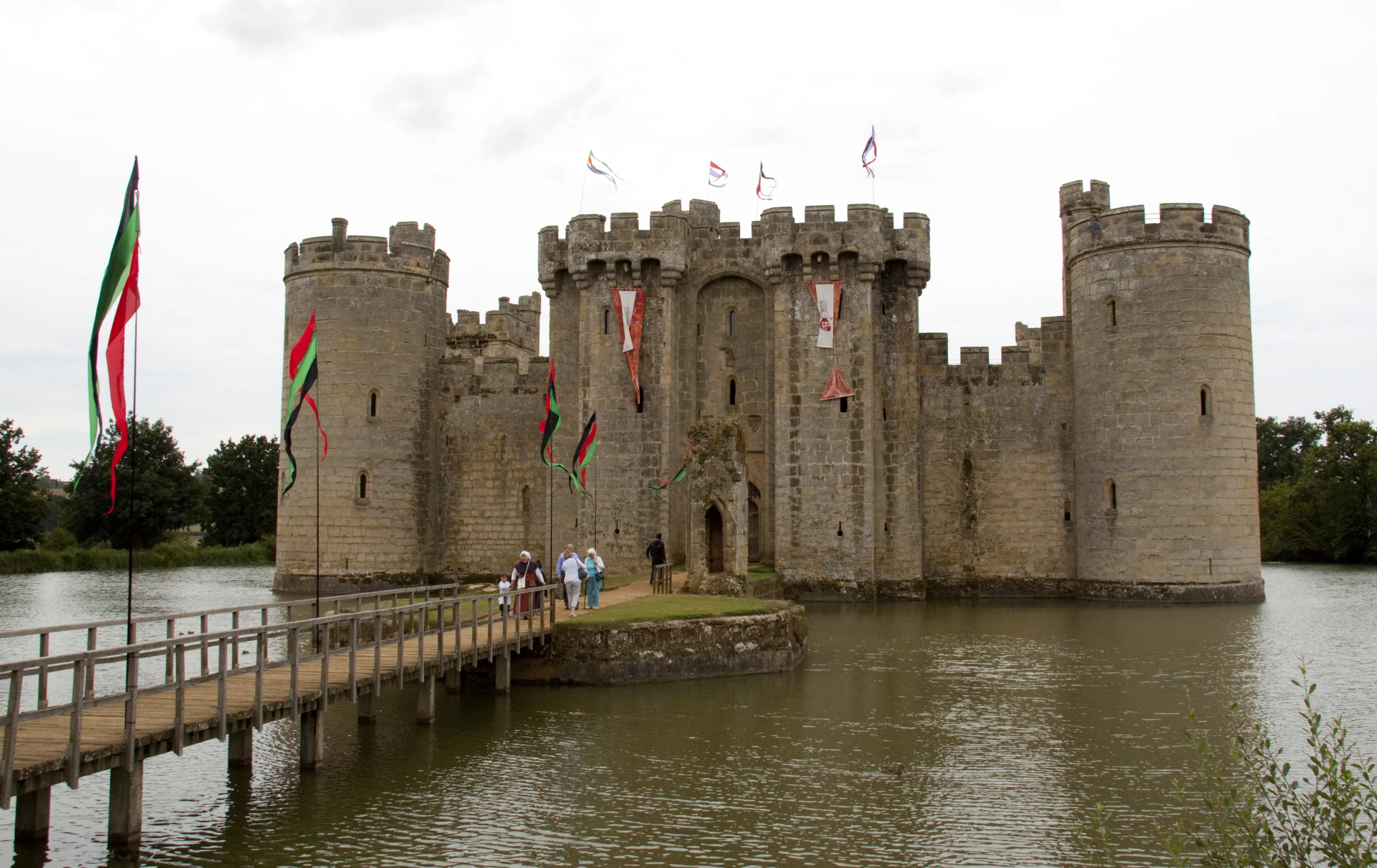 people are walking on the bridge near a moat