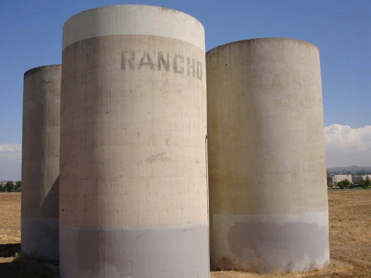 two cement tanks sitting side by side on a dry grass field