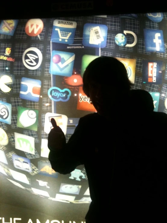 a man looking at a big screen display with various social logos