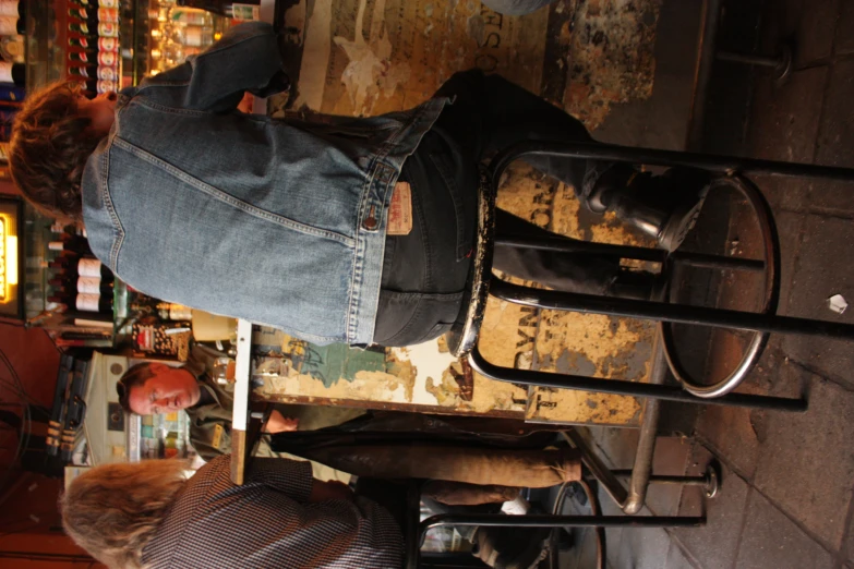 two people sitting at a bar one on the chair and one on the floor