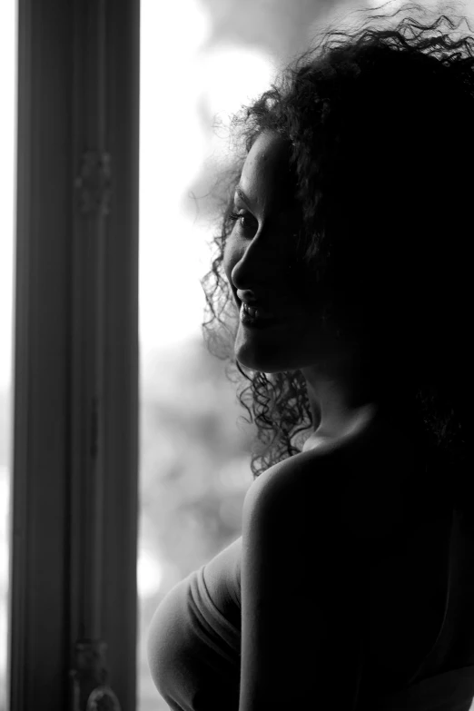 the silhouette of a woman looking out a window