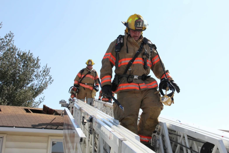 two fire fighters climbing down a staircase to reach the roof