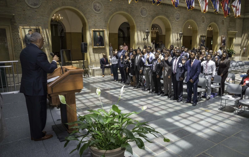 a man speaking at a podium with lots of people