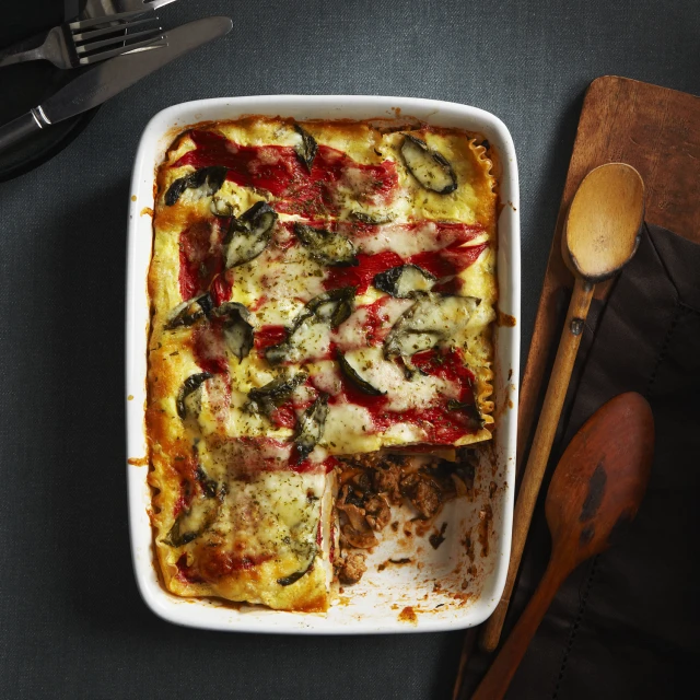 vegetable casserole with bread next to wooden serving utensils