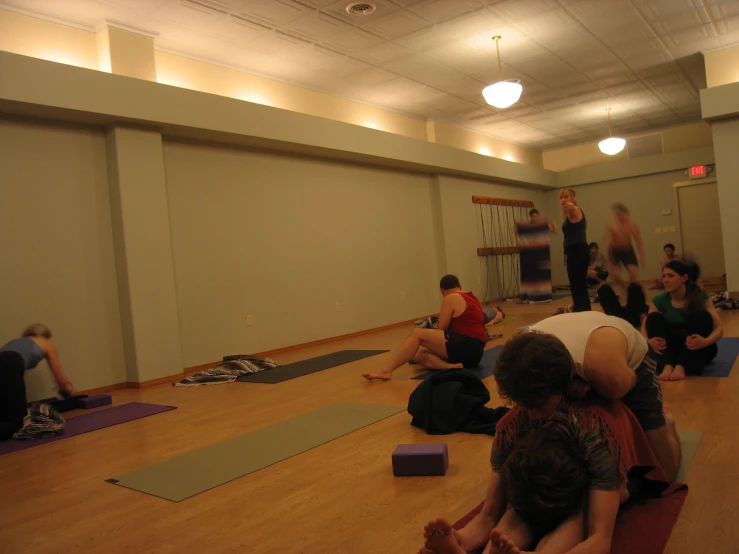 a group of people doing yoga in a room with wooden floors