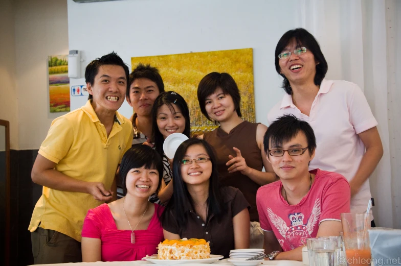 group of people sitting together with a cake