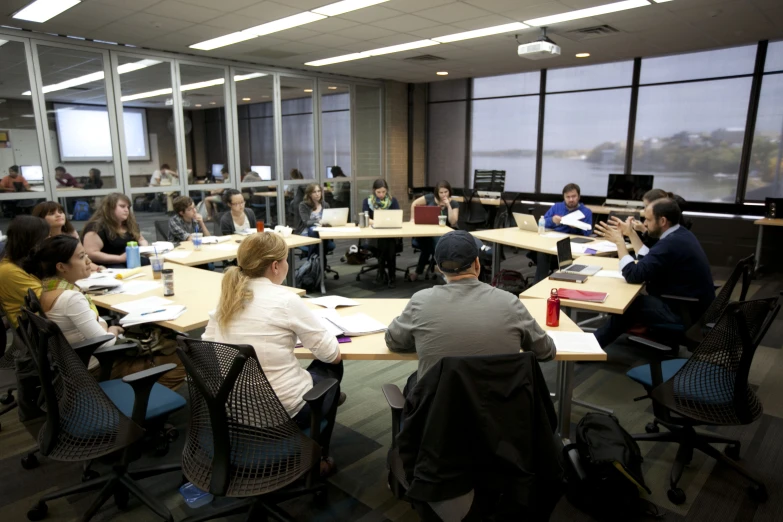 a group of people sitting at a table in front of computers