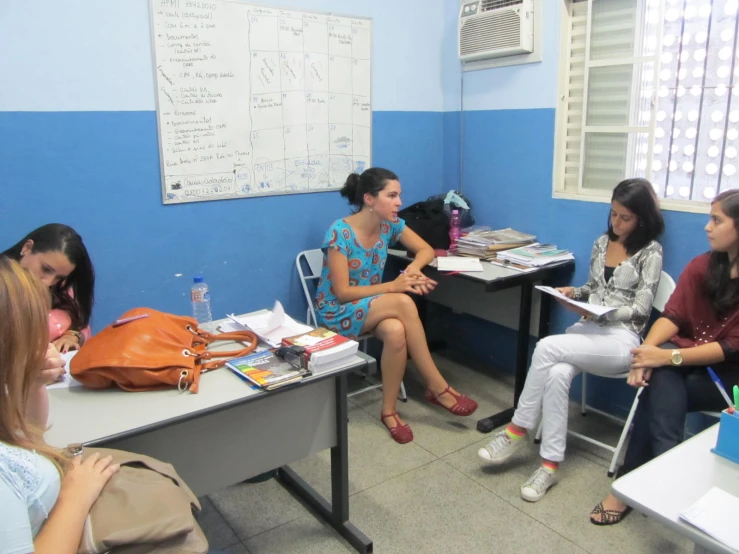 group of young women sitting around a desk talking