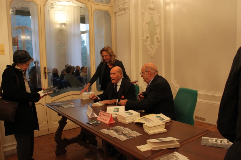 several people stand around and talk around a table