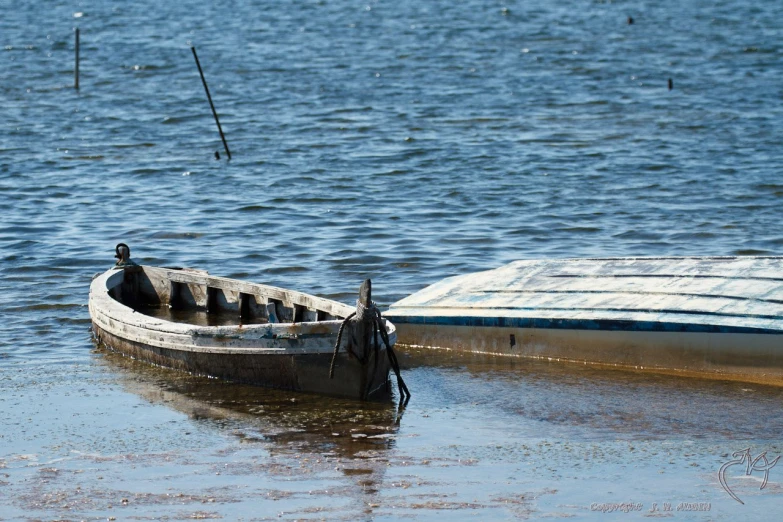 the boat is still on its side as it sits in the shallow water