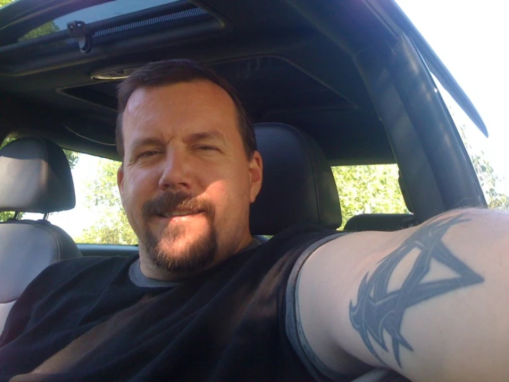 man sitting inside car, smiling for the camera