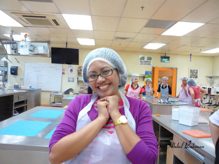 a woman in glasses and a white apron smiling for the camera