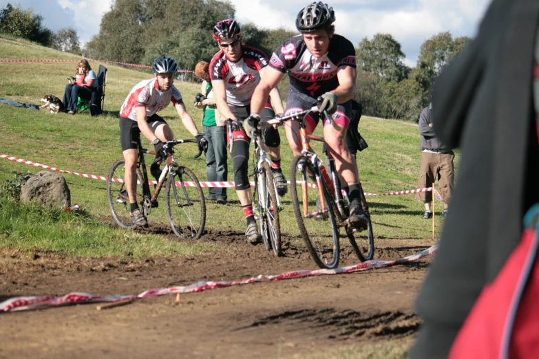 people riding their bicycles around a dirt track