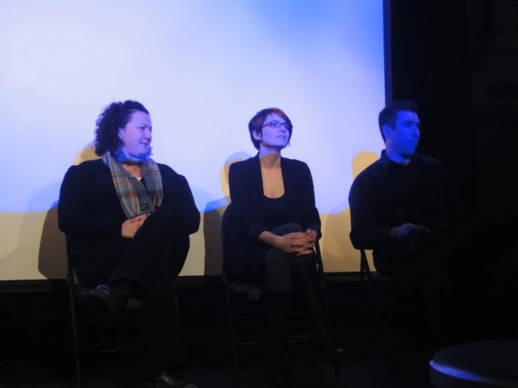 the three people are sitting in chairs with their hands folded