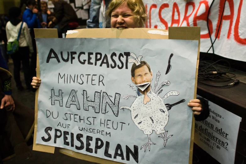 a woman holding a protest poster with pictures on it