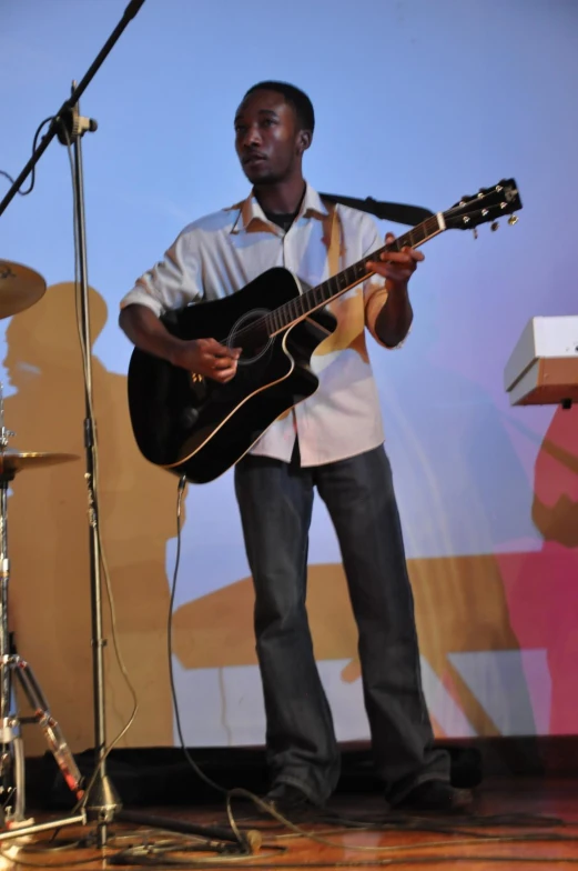 a man holding a guitar and singing into a microphone