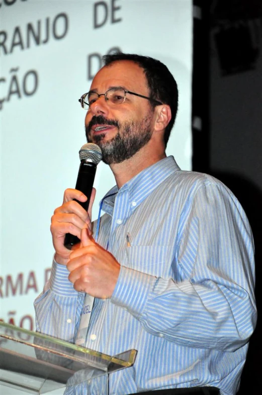 man in blue shirt giving speech at podium