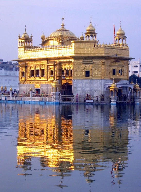 a golden structure is seen on the water in front of buildings