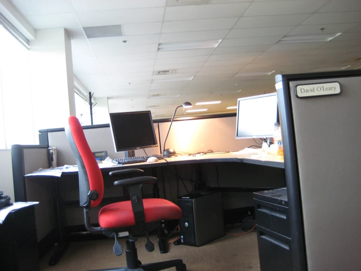 a cubicle office with a red chair and a desk