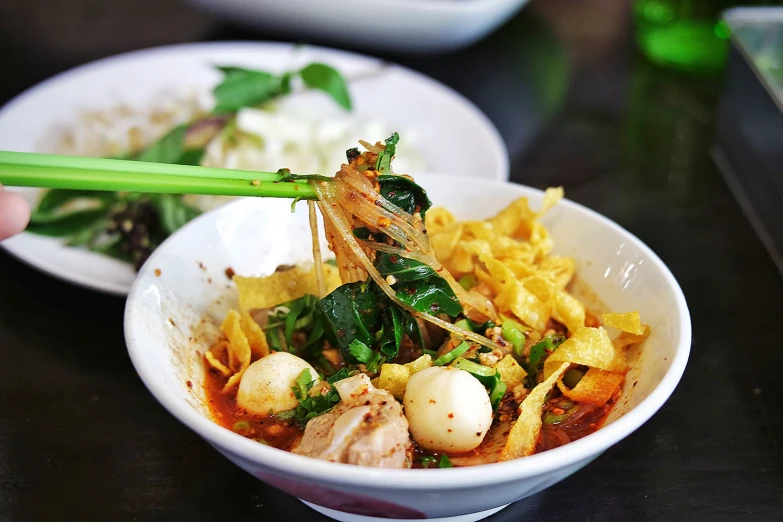 a white bowl filled with vegetables and noodles