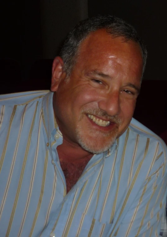 man smiling with white teeth and brown hair in striped shirt