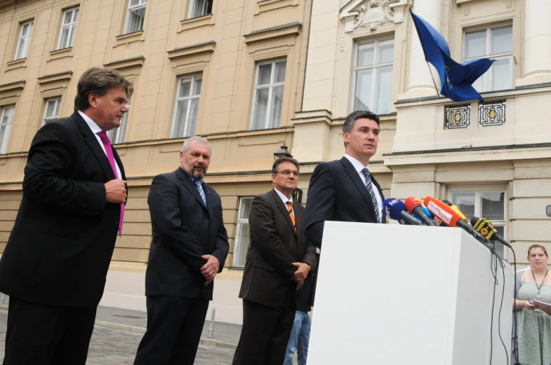 the man is standing behind the podium as people stand around