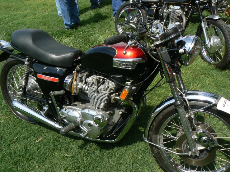 an old black motorcycle sits in the grass