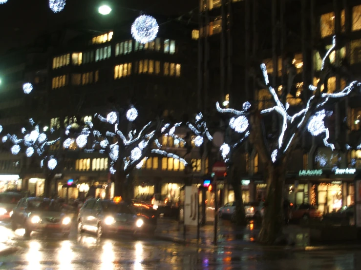 a city at night with light decorations on trees