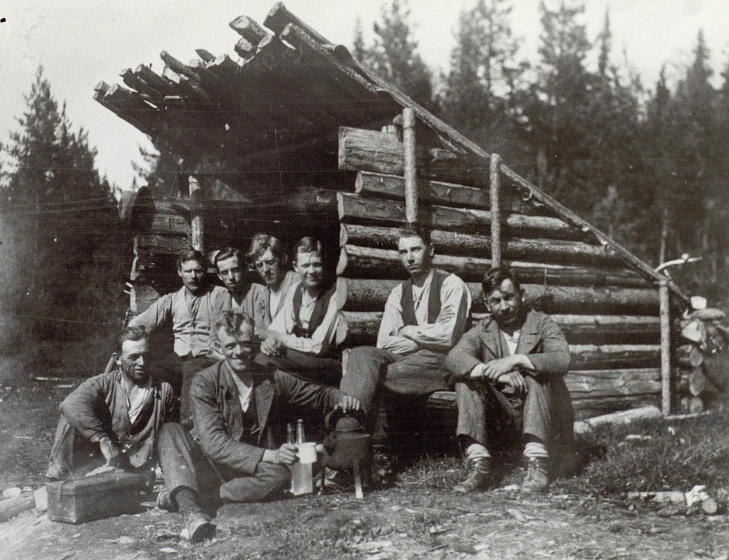 old time pograph of people outside a log cabin