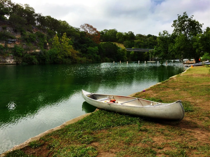 an empty canoe is sitting by a lake