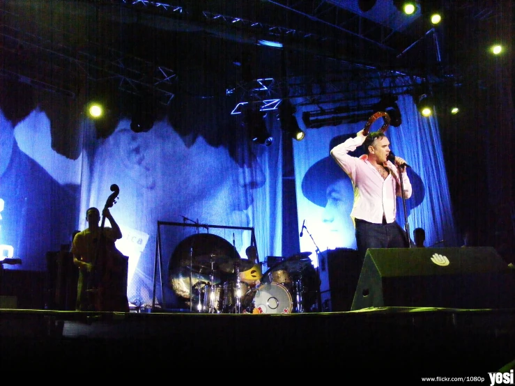 three men playing instruments and singing on stage