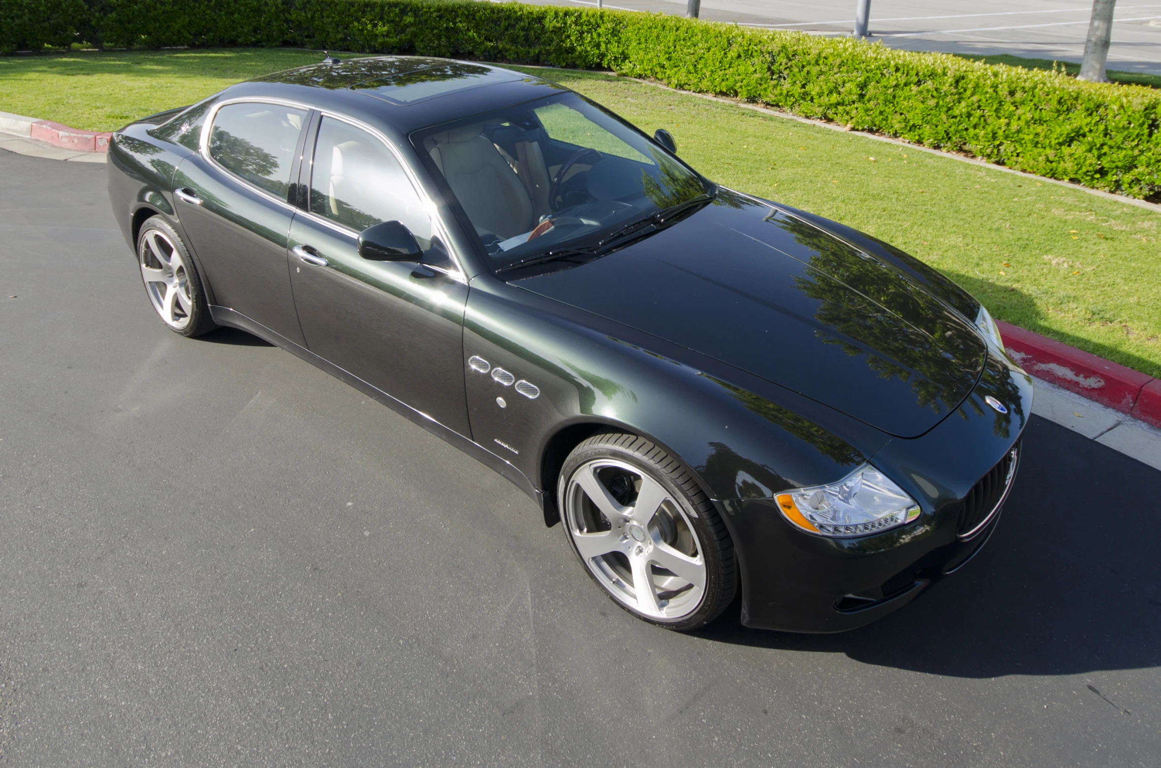 a black bmw parked in front of a red curb