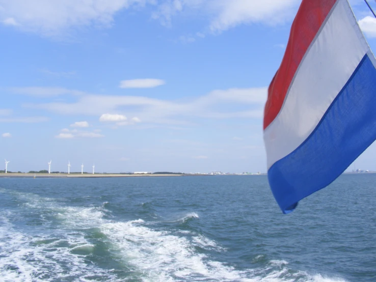 a view of an ocean with some wind mills and a flag in the air