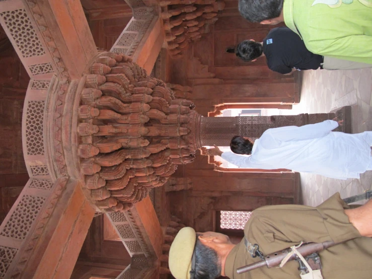 men stand under a carved wooden structure on display