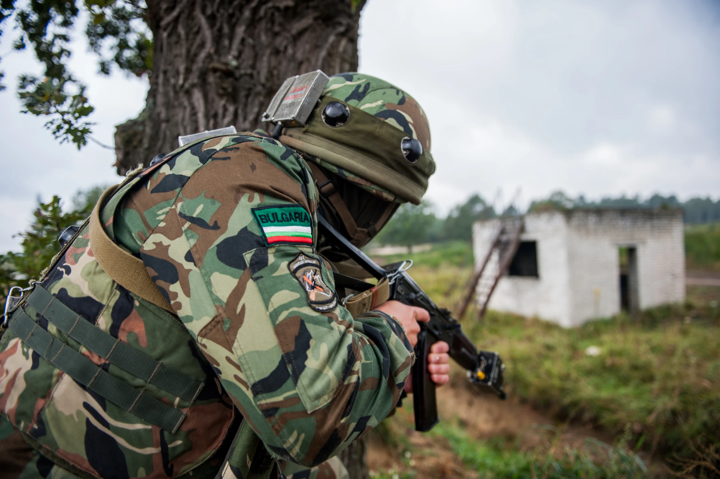 a soldier stands outside with his rifle to the side