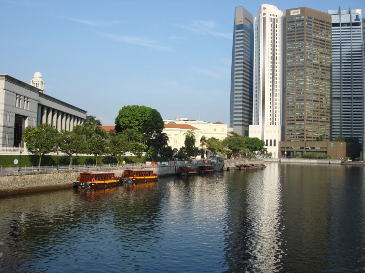 many small boats are floating on the water in front of city buildings