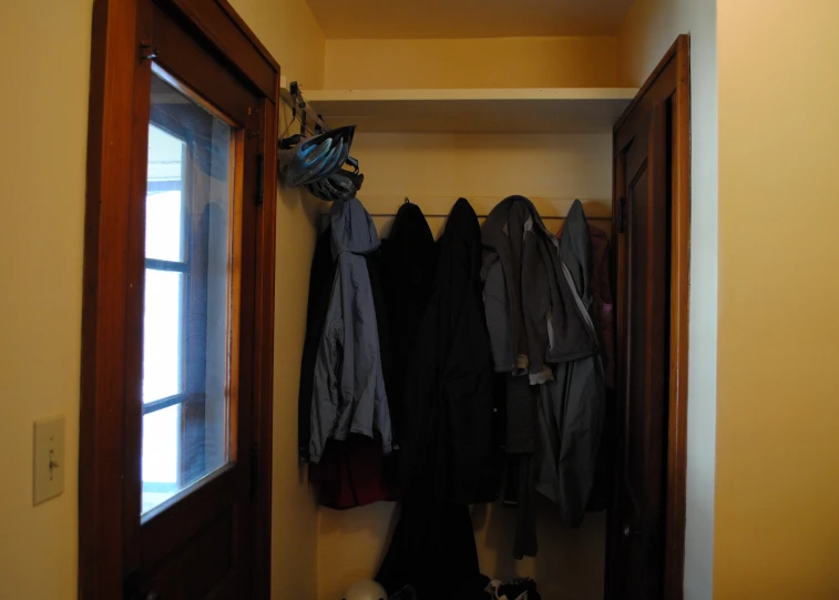 a closet is open with several coats on the shelf