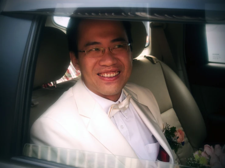 a man in a car with a white suit and tie