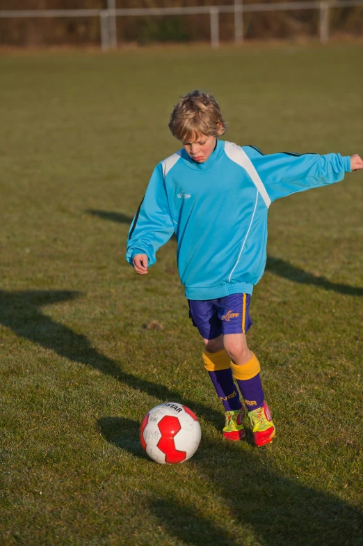 a boy playing with a soccer ball on the field
