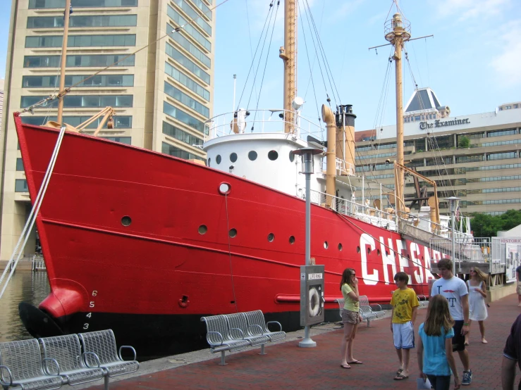 the people are walking in front of a large red boat