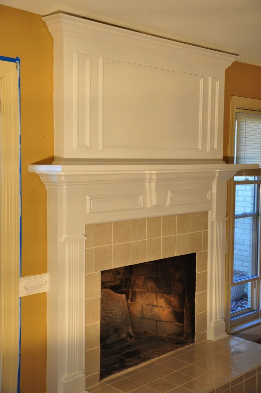 a fireplace with white cupboards above it and a window above