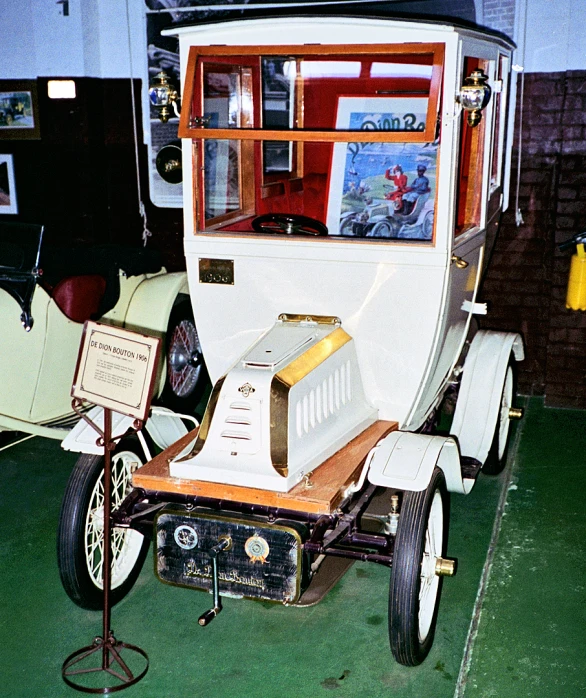 an old white car with wooden interior sitting on a green floor