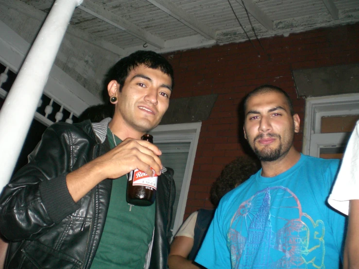 two men standing next to each other while holding a bottle