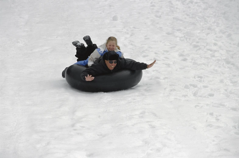 a couple of people on an inner tube in the snow