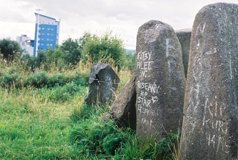 two rock sculptures in grassy field next to a building