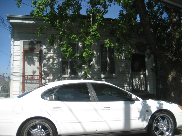 a white car sitting parked near a house on a sunny day