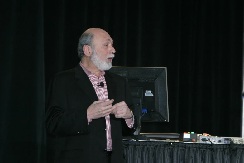 an older man standing next to a computer screen