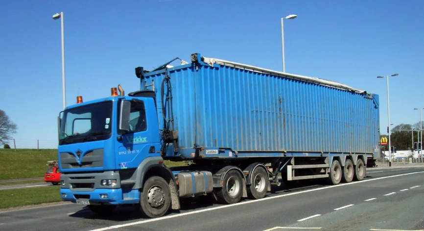 a blue delivery truck driving down a city street