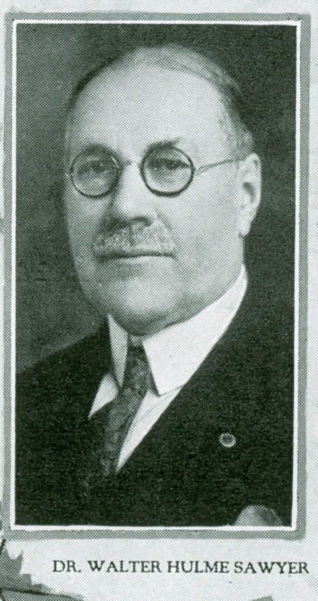 a portrait of a man wearing glasses, tie, and suit jacket